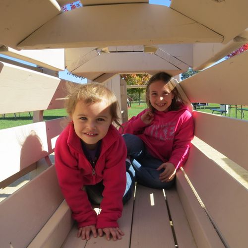 A woman in her wedding dress is sitting on the beach with flowers.