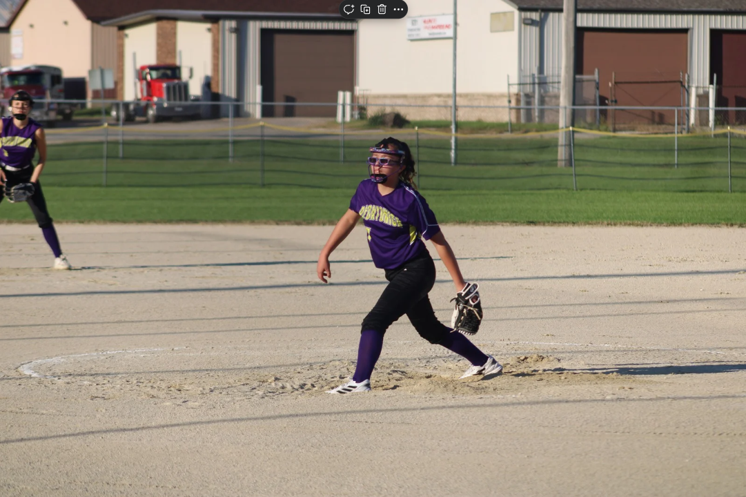 A woman in a wedding dress is standing in front of the sea on the rocks.