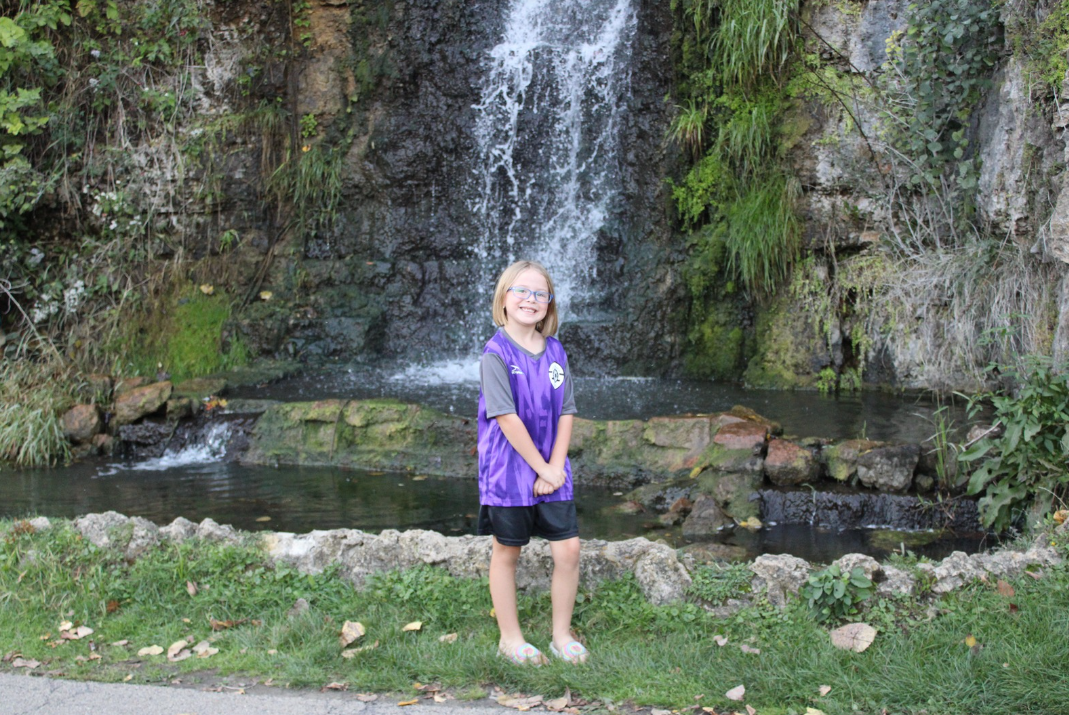 Black and white photo of a woman in a wedding dress in a room in front of a mirror from the back.